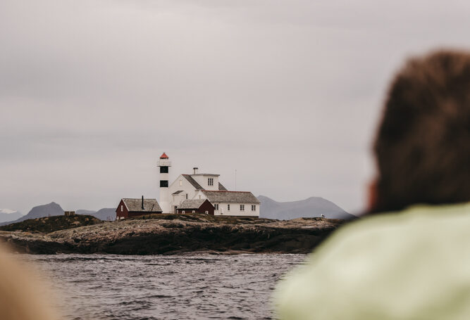 Flatflesa Fyr fotografert fra båt, omgitt av hav og lave bølger.