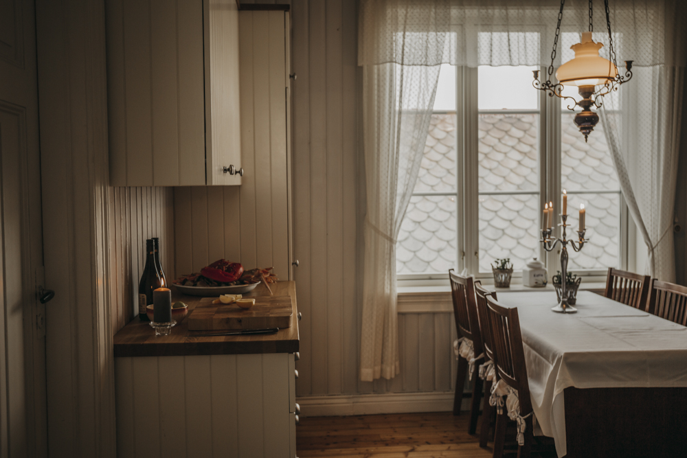 Interiør på Flatflesa Fyr med spisebord, vindu og lysekrone.