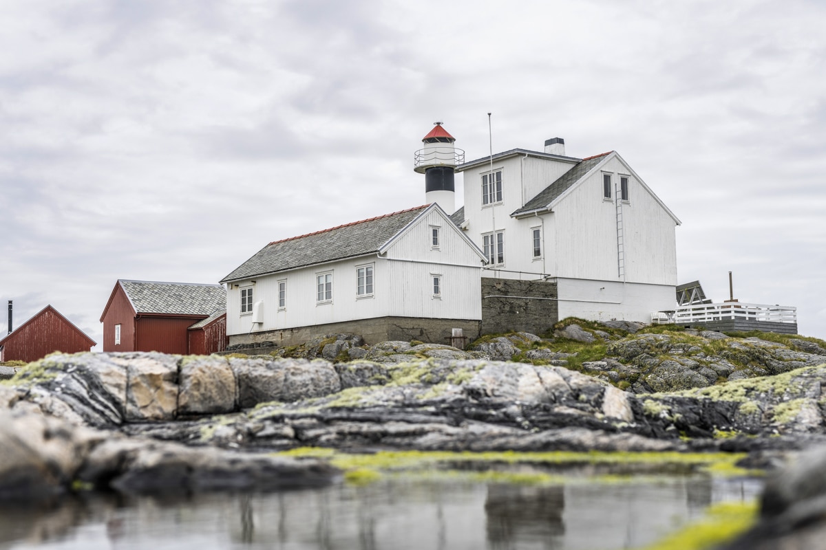 Lighthouse on a rocky island surrounded by the ocean on the Norwegian coast.